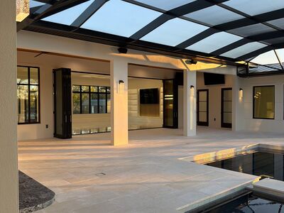 Large screened in porch with large doors leading into a smaller covered area.